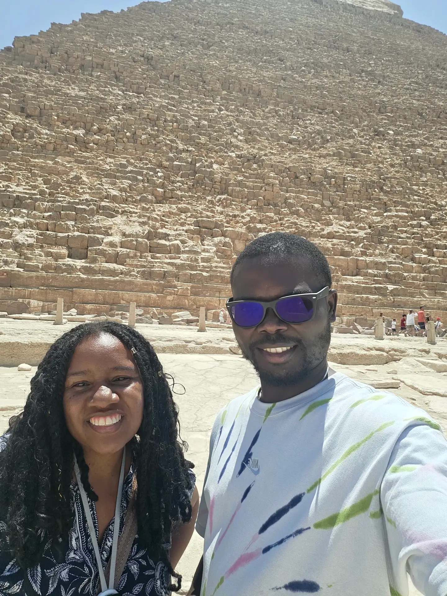 Deja and her husband smiling in front of the Pyramids of Giza