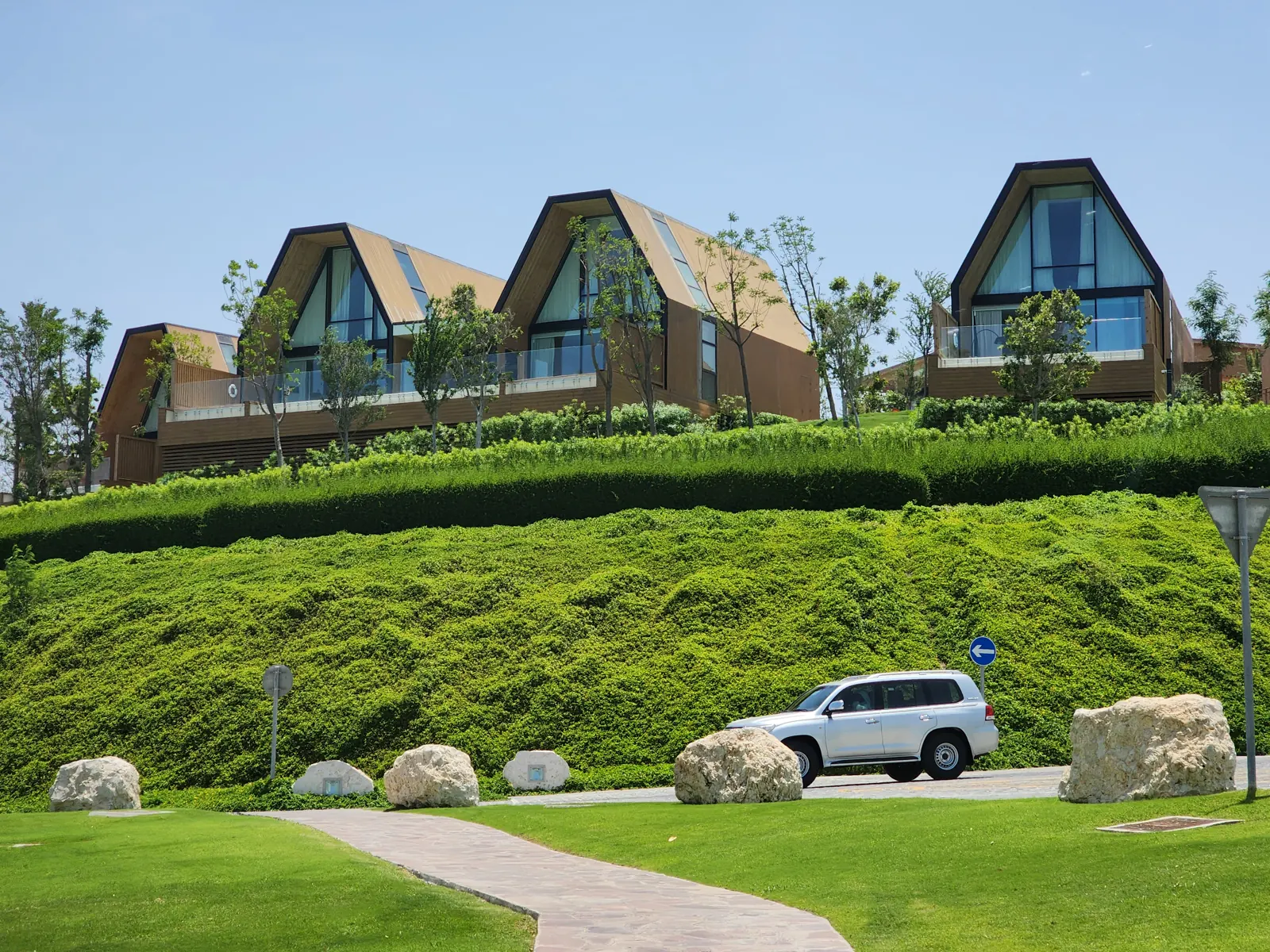 Wood-clad Katara Hills villas on a green hillside in Doha