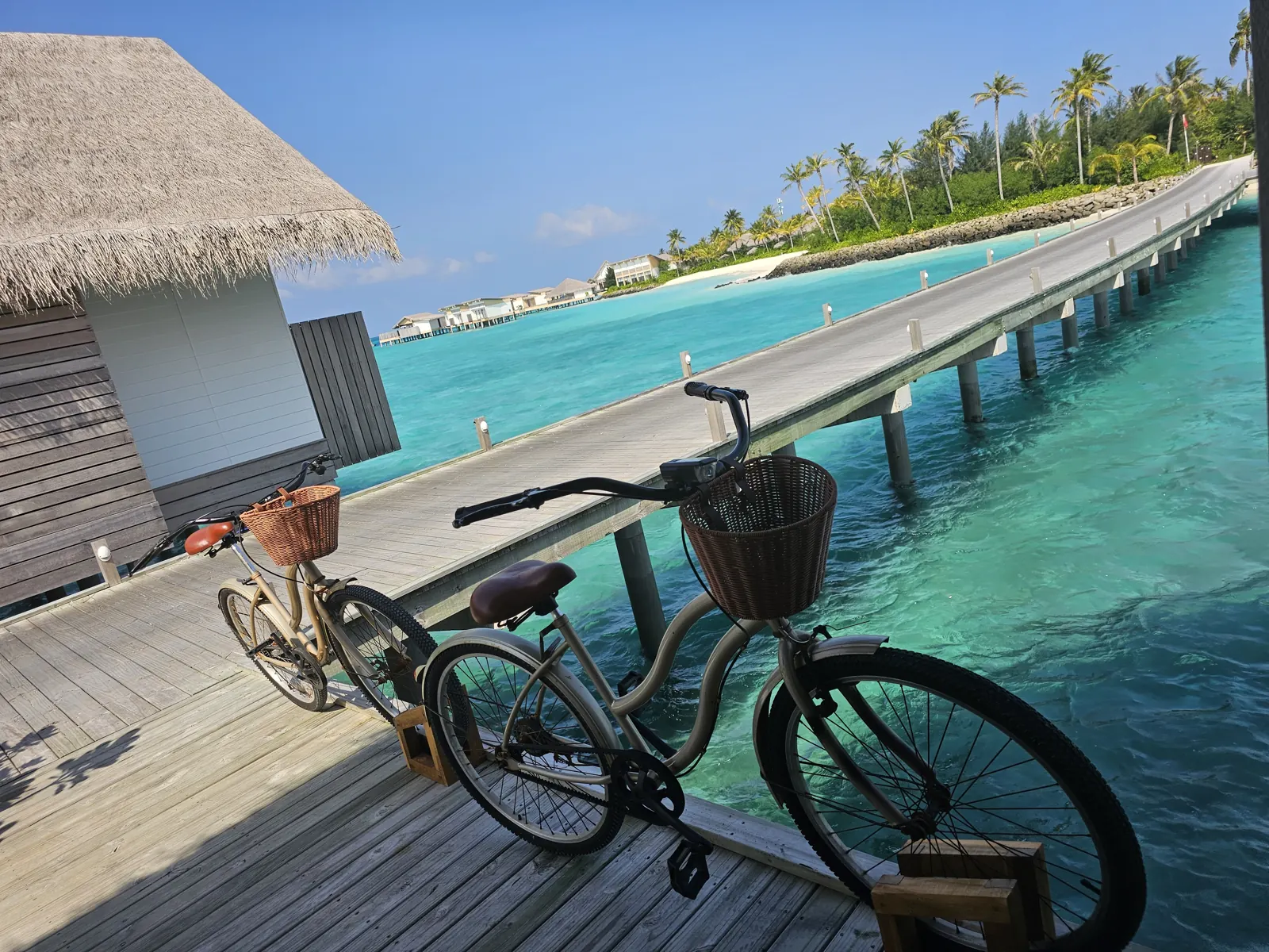 A bicycle parked on a wooden overwater walkway above turquoise water at Hilton Maldives Amingiri