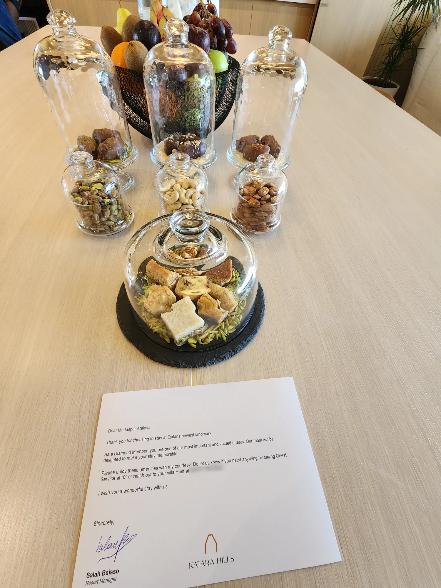 Welcome treats under glass domes, a fruit bowl and a welcome note from the resort manager on the villa table