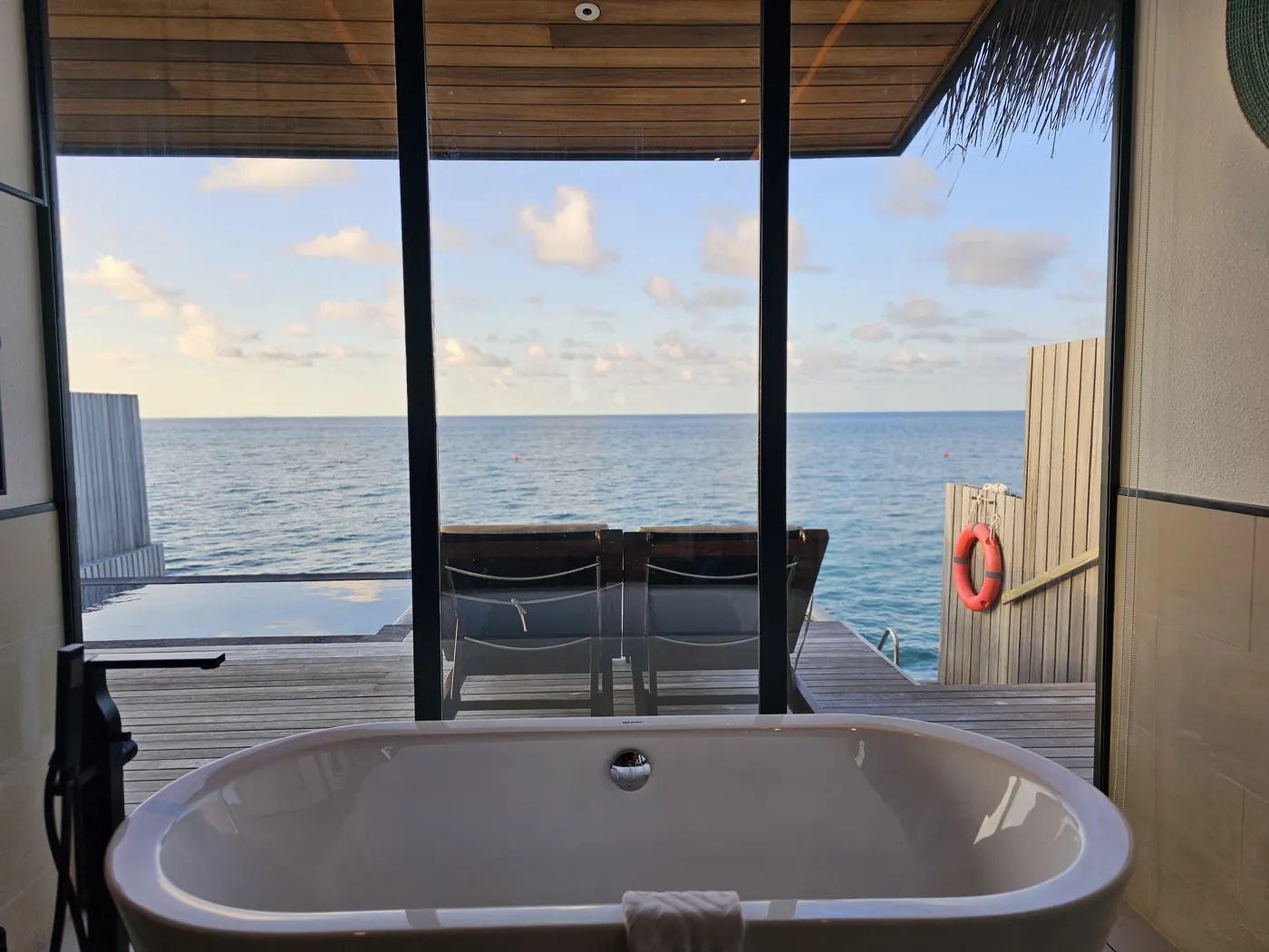 A freestanding bathtub facing an open view of the ocean in an overwater villa
