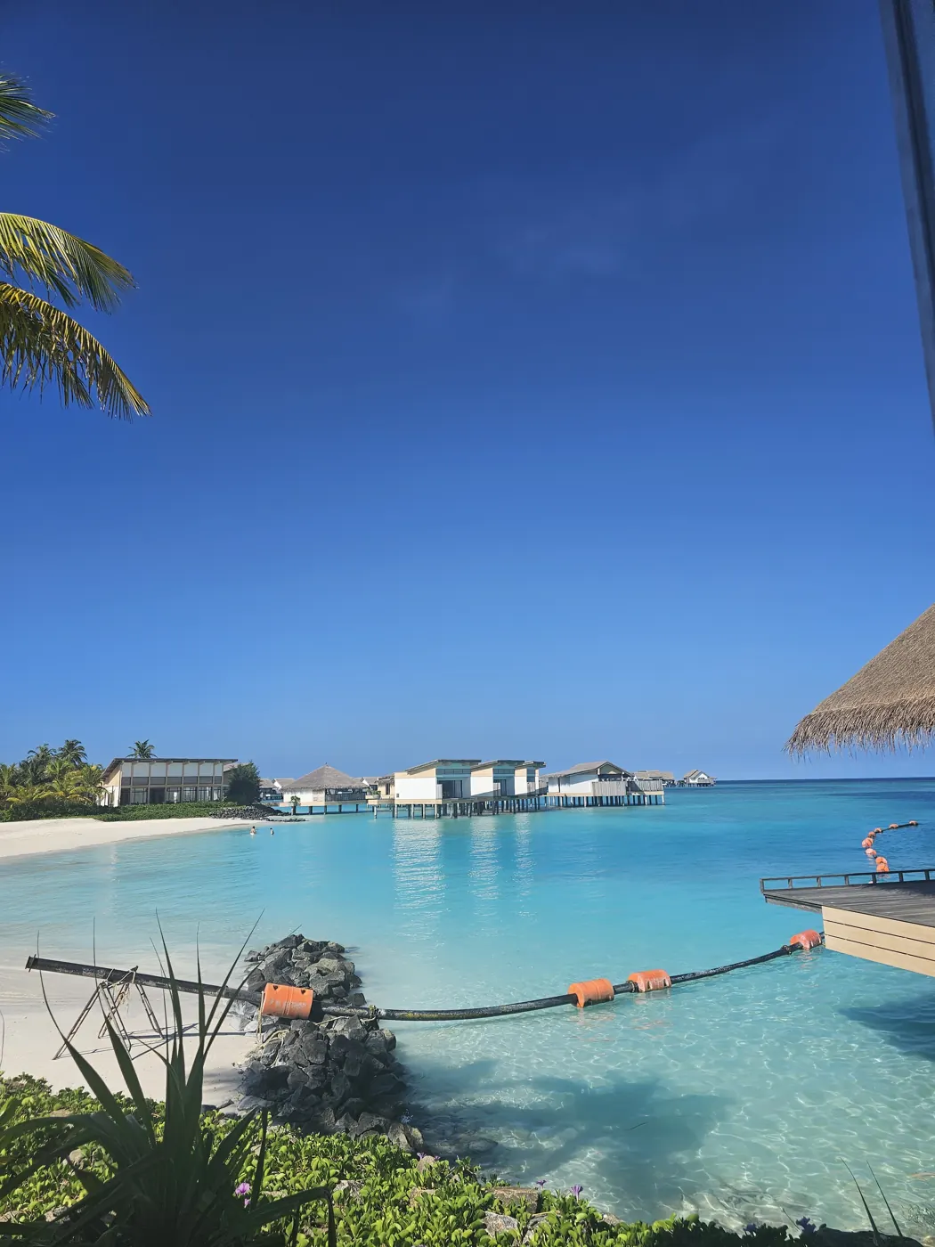 A turquoise lagoon with overwater villas in the distance at Hilton Maldives Amingiri